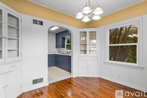 A kitchen with white cabinets and a wooden floor.