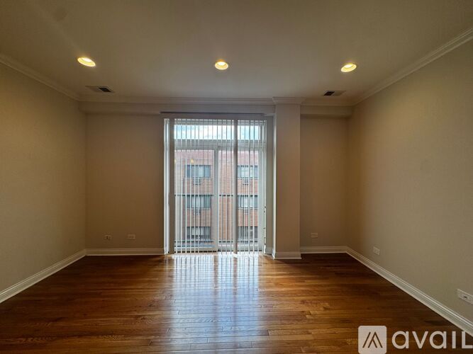 A spacious room with wooden floors and a large window with a view of a building outside.