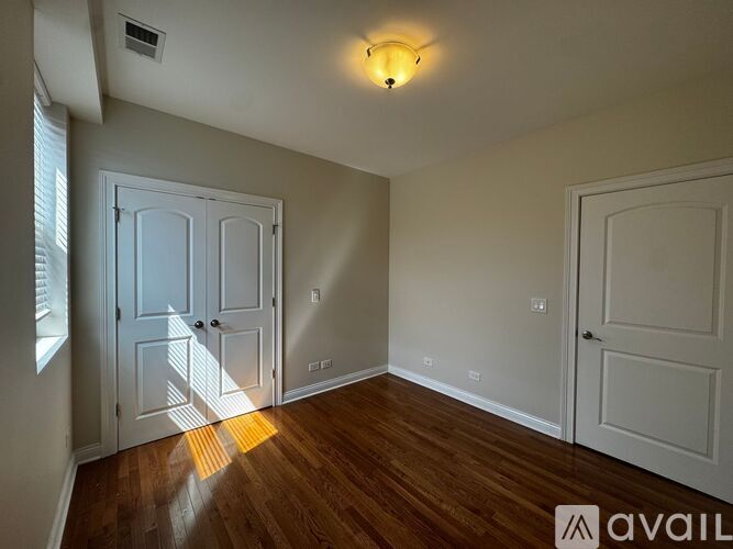 A room with wooden floors and white walls has two doors and a window.
