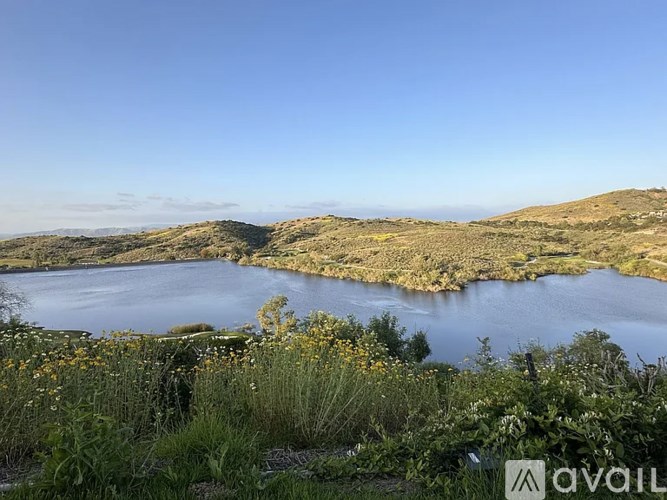 A lake surrounded by greenery under a clear sky.