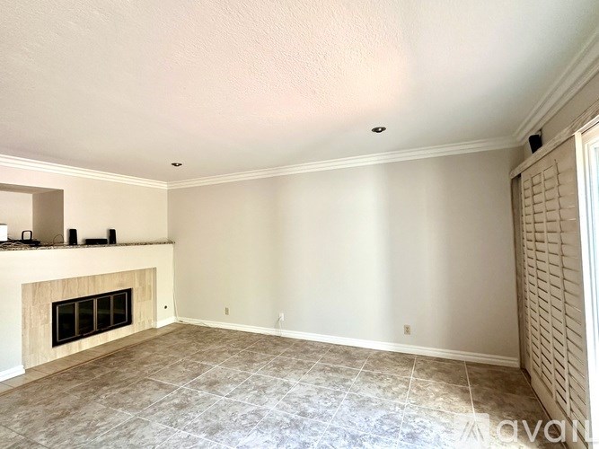 A living room with a fireplace and tiled floor.