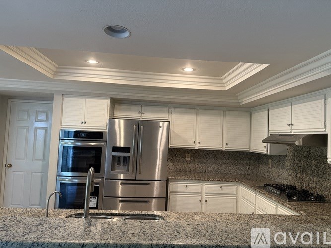 A bathroom with a granite countertop and white cabinets.