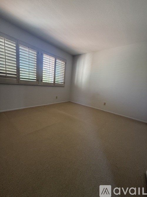 A room with beige carpet and a window with blinds.