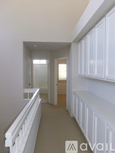 A hallway with white railings and a white door.