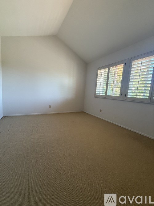 A room with a carpeted floor and a window with blinds.