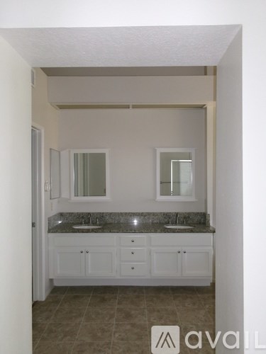 A bathroom with a granite countertop and white cabinets.
