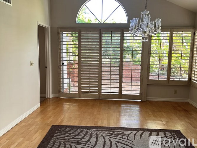 A room with a chandelier, sliding glass doors, and a rug on the floor.