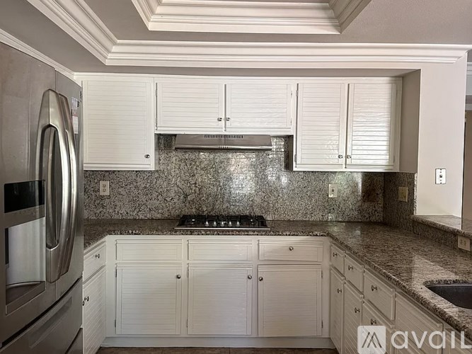 A kitchen with white cabinets and a granite countertop.