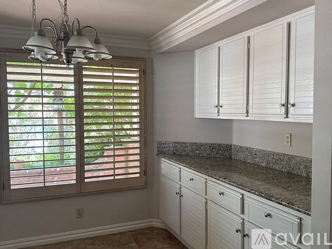 A kitchen with white cabinets and a granite countertop.