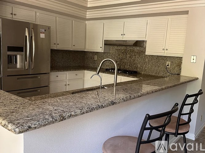 A kitchen with granite countertops and a stainless steel refrigerator.