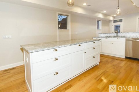 A kitchen with white cabinets and a wooden floor.