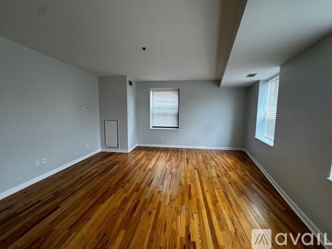 A room with wooden flooring and a window with blinds.