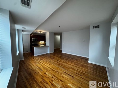 A room with wooden floors and white walls, with a bar area in the corner.