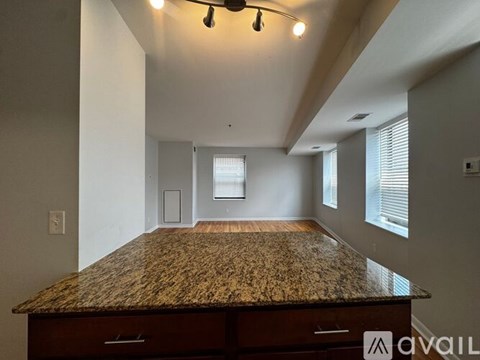 A spacious room with a granite countertop and a window with blinds.