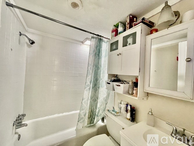 A bathroom with a white tub, sink, and shower curtain.