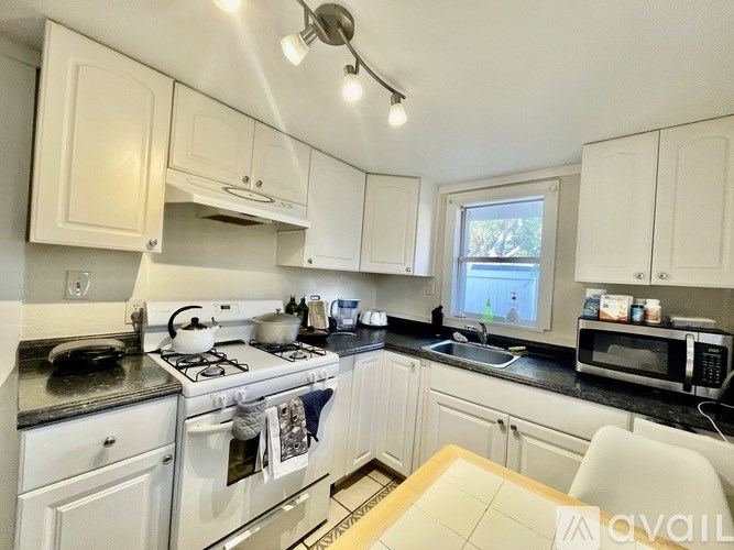 A kitchen with white cabinets and black countertops.