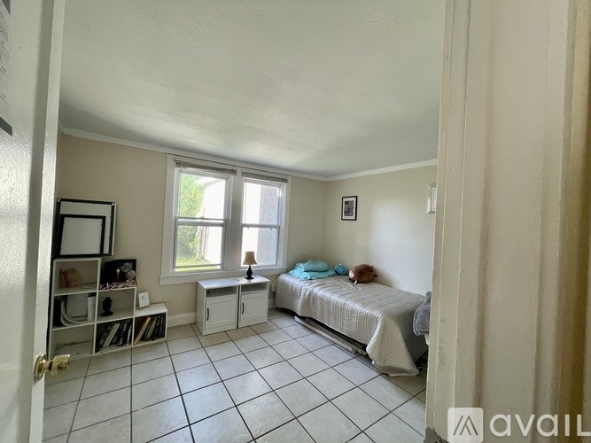 A bedroom with a bed, a bench, and a window.