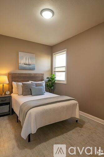 A bedroom with a bed, nightstand, and a painting of a sailboat on the wall.