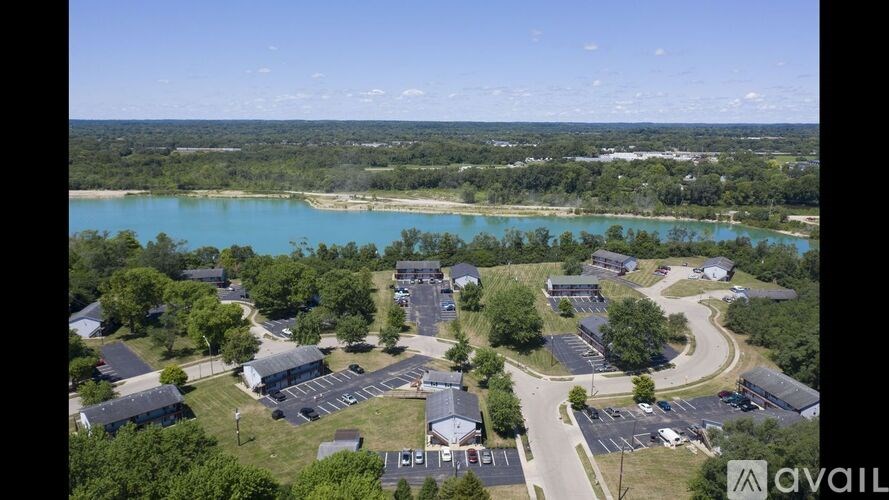 A bird's eye view of a parking lot and buildings with a body of water in the distance.