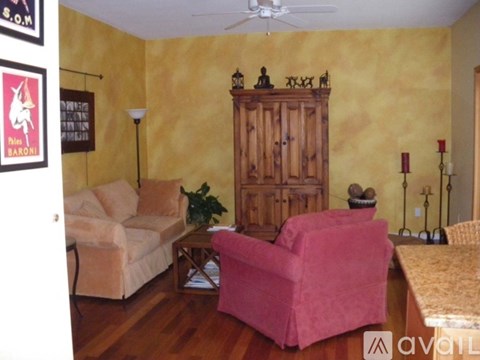 A living room with a pink chair and a wooden cabinet.