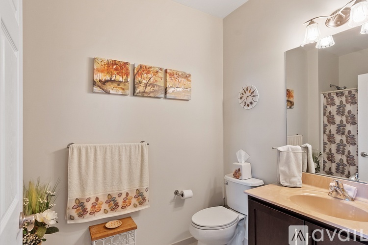 A bathroom with a toilet, sink, and a shower curtain with a leaf pattern.