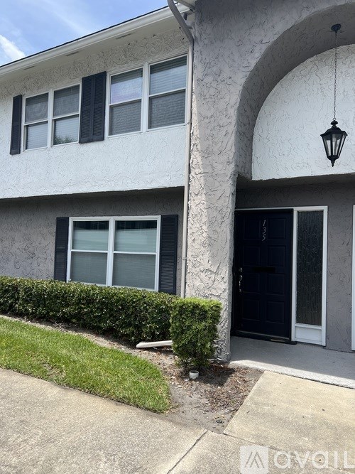 A white house with a black door and a black lamp.