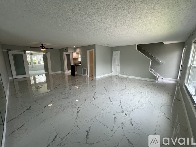 A spacious room with marble flooring and a staircase on the right side.