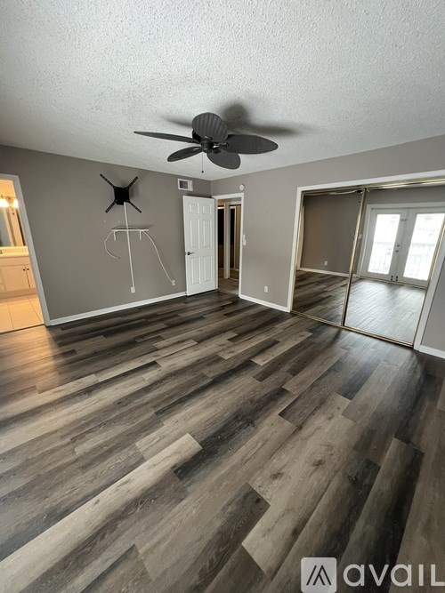 A room with a ceiling fan and wooden flooring.