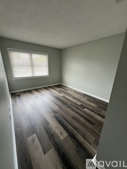 A room with wooden flooring and a window with blinds.