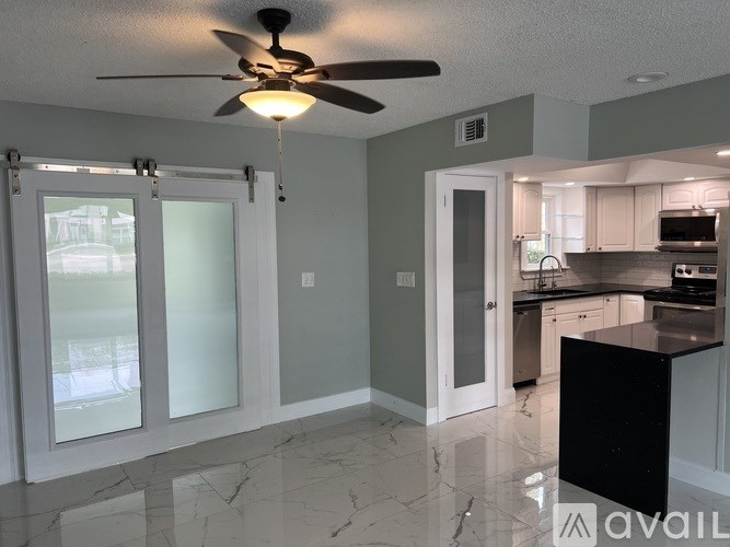 A kitchen with a black counter and a ceiling fan.