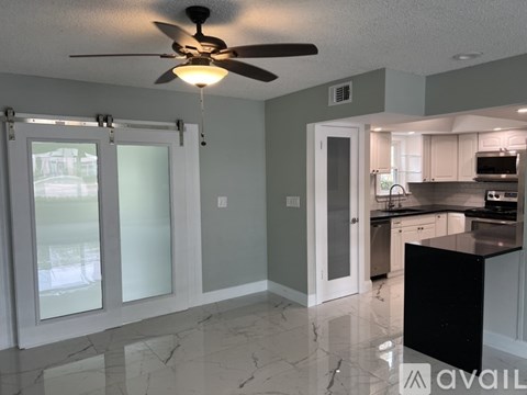 A kitchen with a black counter and a ceiling fan.