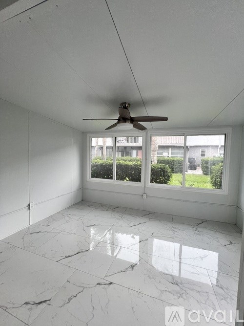 A room with a ceiling fan and marble flooring.