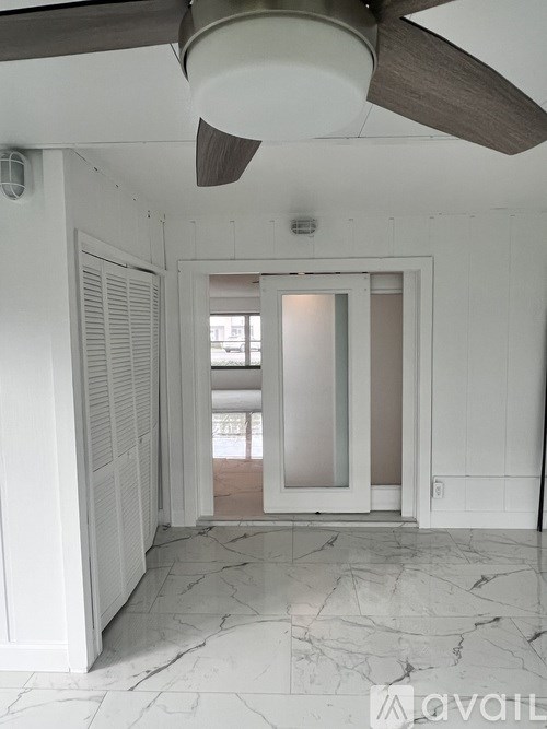 A room with a ceiling fan and marble flooring.