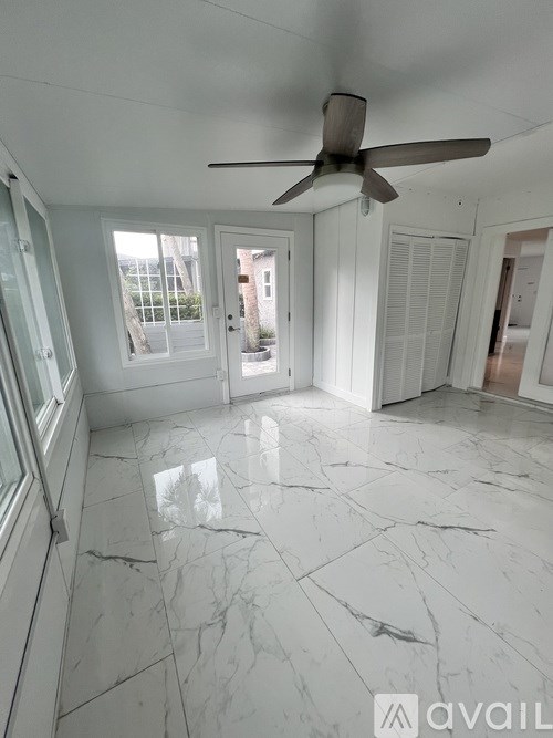 A spacious room with a marble floor and a ceiling fan.