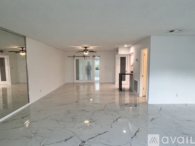 A spacious room with marble flooring and a ceiling fan.