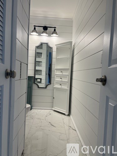 A white bathroom with a mirror and lights above it.