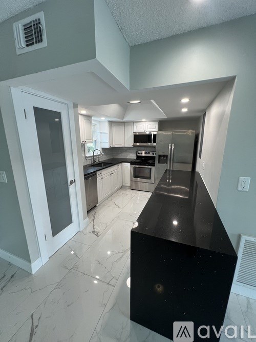 A kitchen with a black countertop and white cabinets.