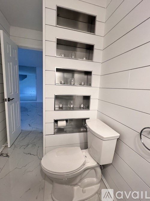 A white toilet in a bathroom with a white wall and a white towel rack.