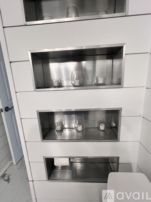 A white cabinet with three shelves, each containing glasses.