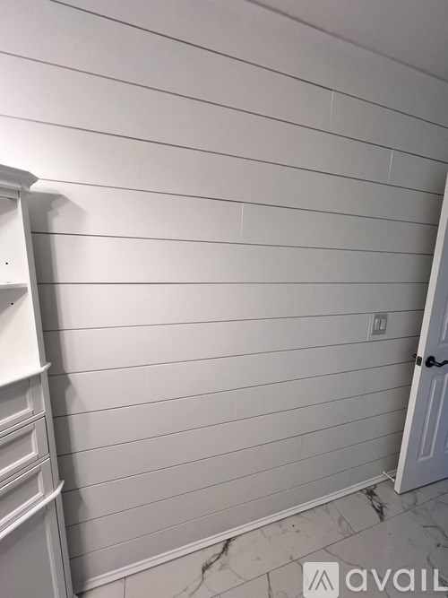 A white wall with a door and a shelf.