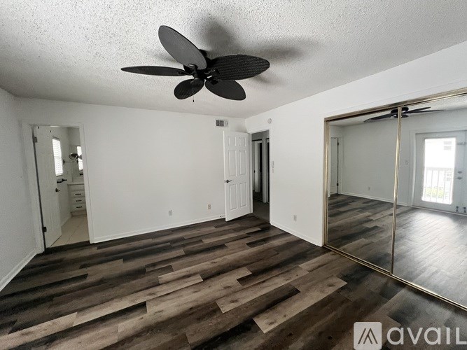 A room with a ceiling fan and wooden flooring.