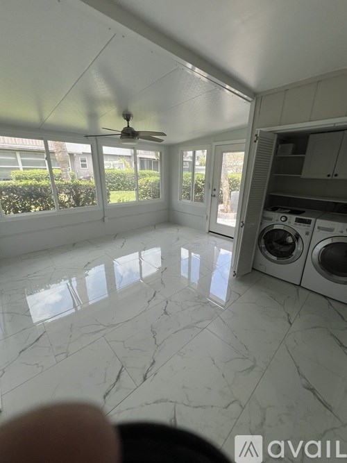 A sunny day in a room with a marble floor and a ceiling fan.