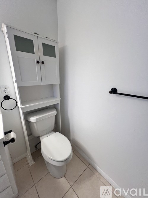 A white toilet with a white cabinet above it in a bathroom.