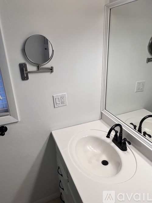 A white sink in a bathroom with a round mirror above it.