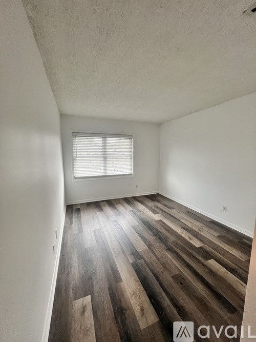 A room with wooden flooring and a window with blinds.