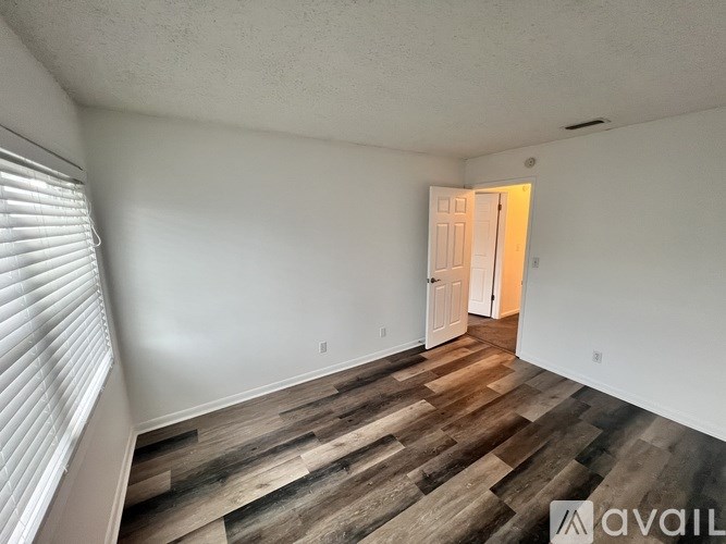 A room with wooden flooring and a doorway leading to another room.