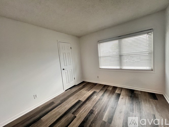 A room with wooden flooring and a window with blinds.