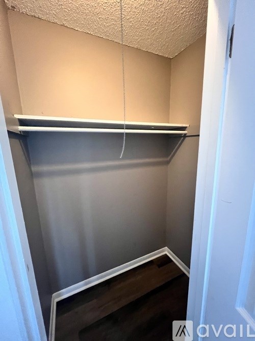 A small, empty closet with a single shelf and a door.