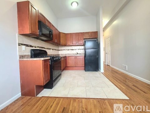 A kitchen with wooden cabinets and a black refrigerator.