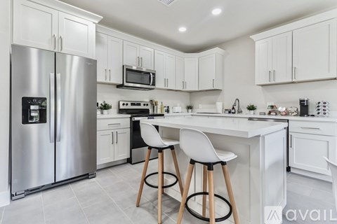 A modern kitchen with white cabinets and a stainless steel refrigerator.
